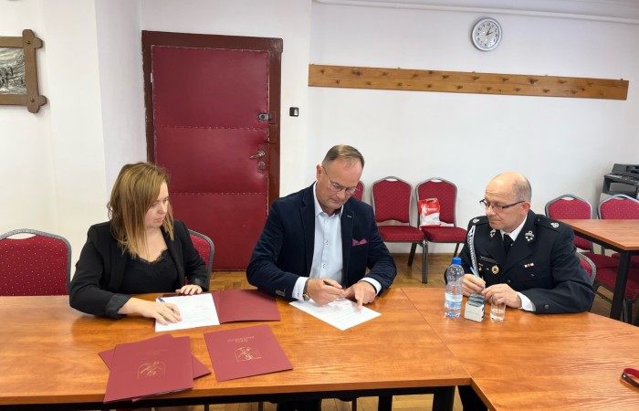 Wójt oraz strażak podpisują dokumenty przy stole