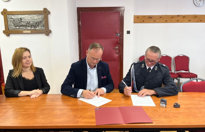 Wójt oraz strażak podpisują dokumenty przy stole